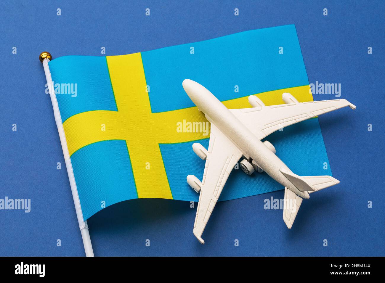 Drapeau de Suède et avion jouet sur fond bleu, concept sur le thème du voyage en Suède Banque D'Images