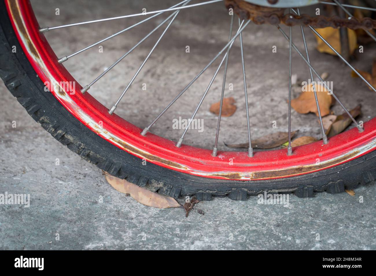 Gros plan d'un pneu de vélo plat vieux et rouille sur fond de ciment Banque D'Images