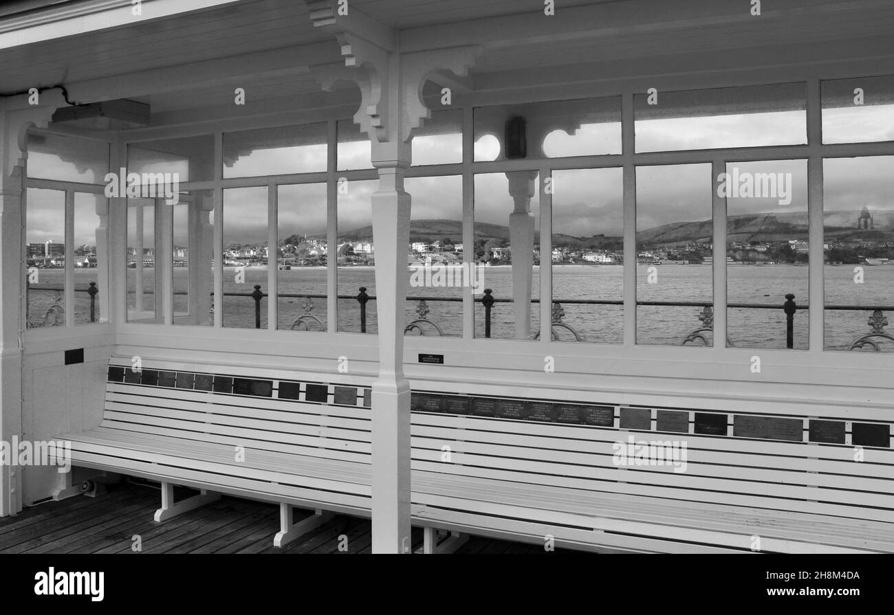 Vue rapprochée des sièges et du refuge sur Swanage Pier, Dorset, Angleterre avec la ville en arrière-plan. Banque D'Images