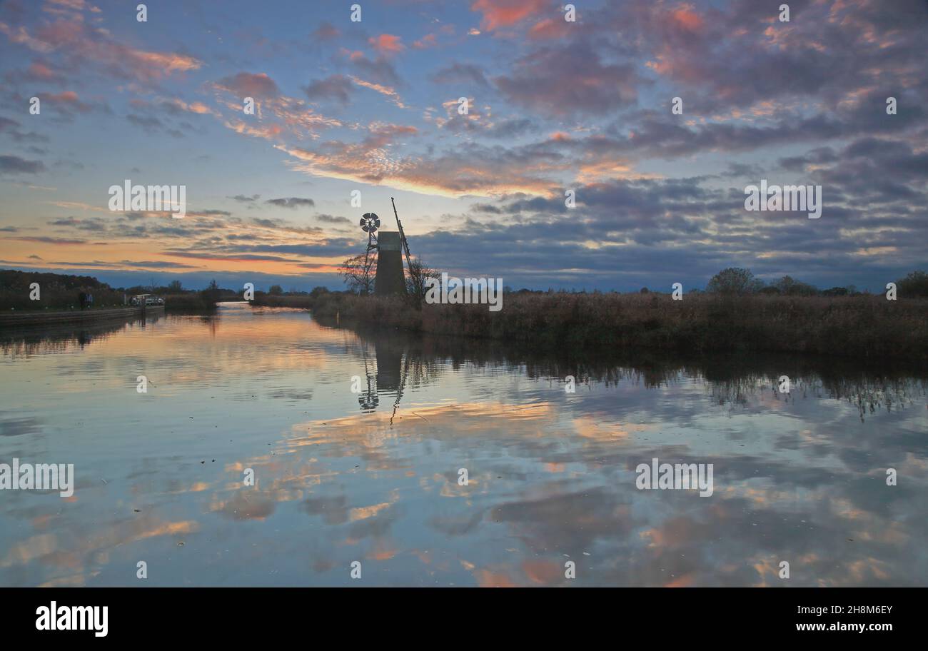 Une vue sur la rivière Ant sur les Norfolk Broads en automne au crépuscule après le coucher du soleil avec un moulin à vent emblématique vu de How Hill, Ludham, Norfolk, Angleterre, Royaume-Uni. Banque D'Images