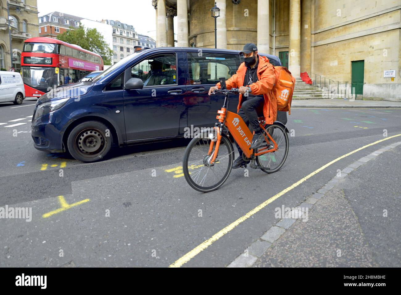 Londres, Angleterre, Royaume-Uni.Il suffit de manger un cycliste de livraison à Langham place Banque D'Images