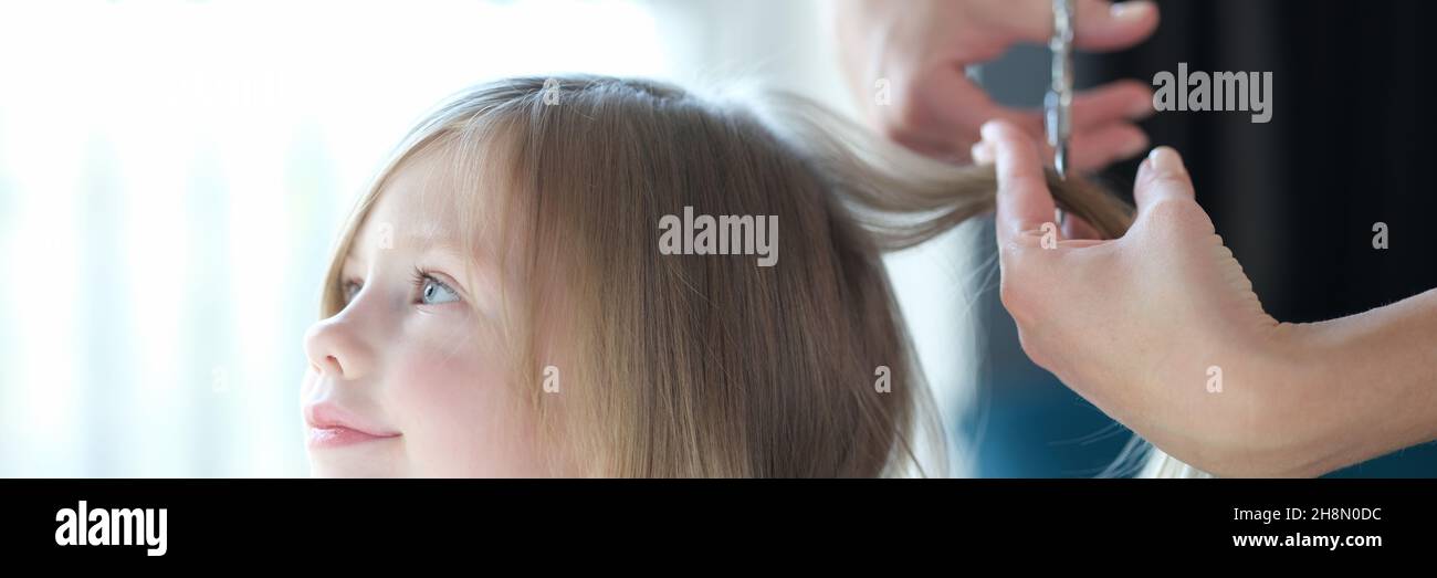 Belle petite fille coiffeur coupe les cheveux gros plan Banque D'Images