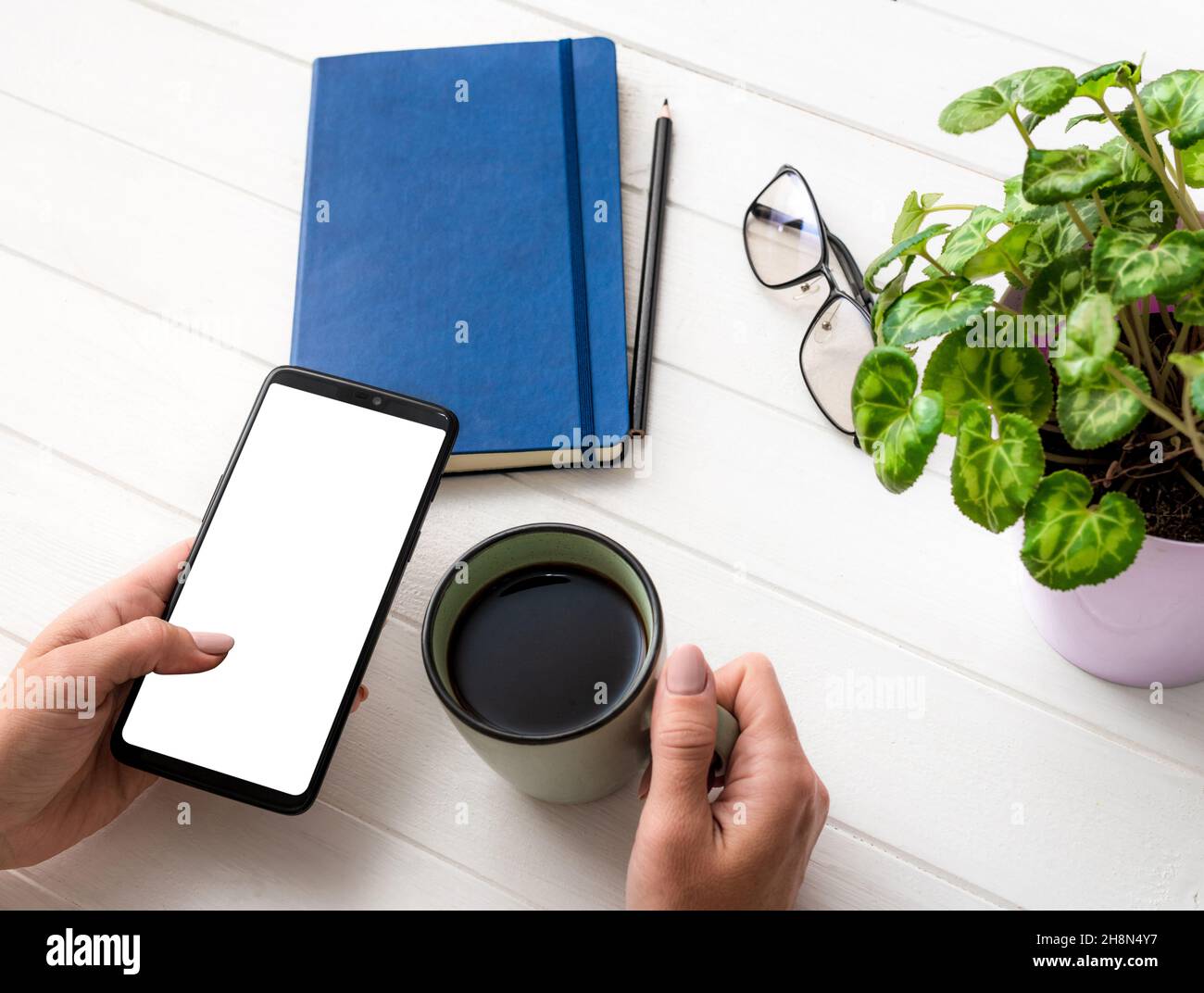 Vue de dessus d'une fille utilisant un smartphone et tenant une tasse à café sur le lieu de travail Banque D'Images