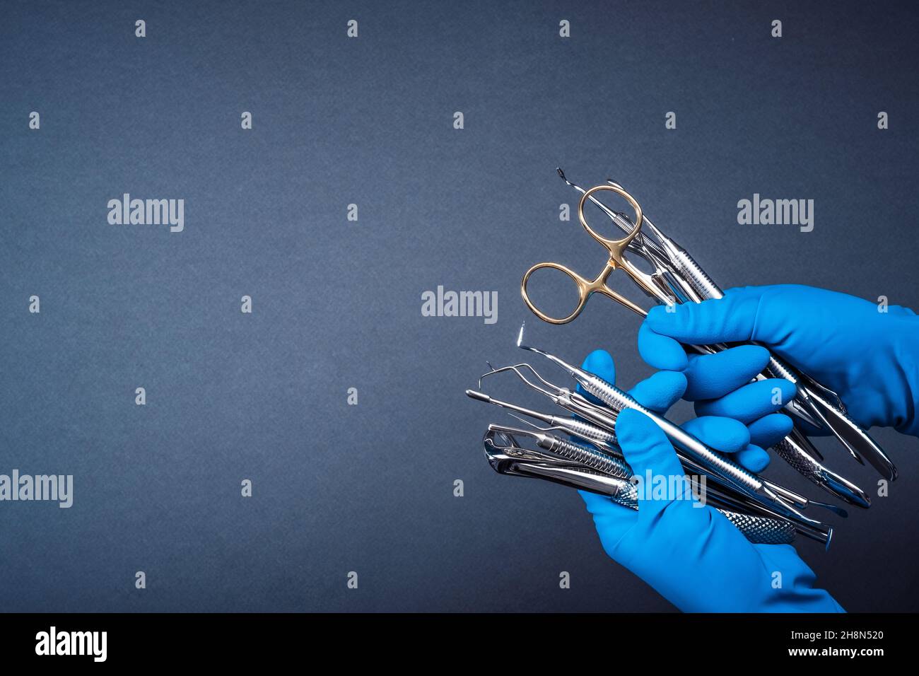 Mains dans des gants bleus tenant l'équipement dentaire en métal Banque D'Images