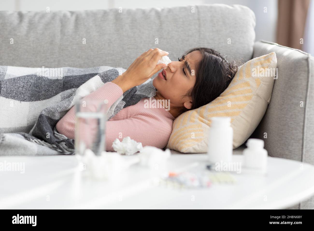 Une femme indienne millénaire dépairée, couverte de couverture, souffre de la grippe souffle le nez dans la serviette Banque D'Images
