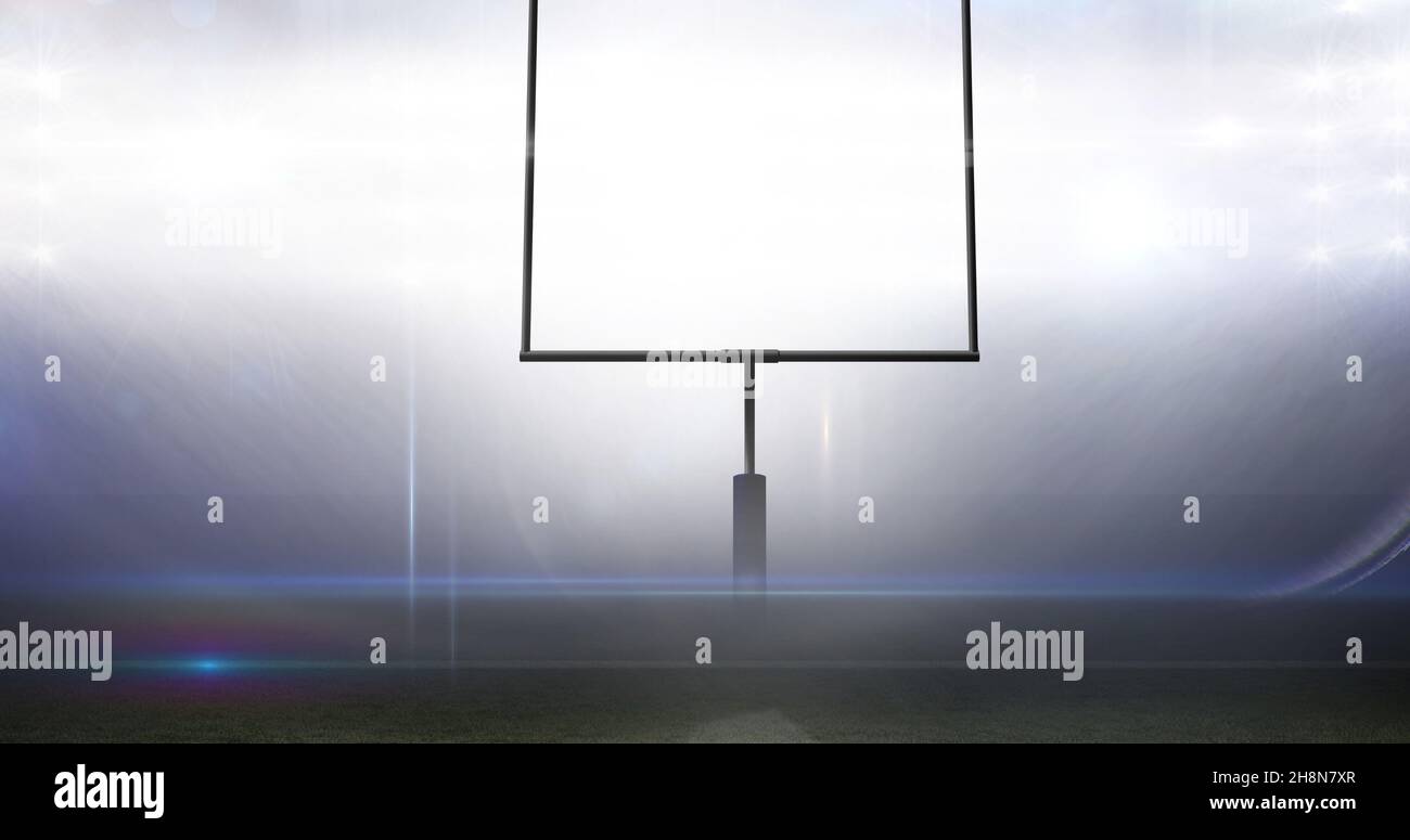 Un poteau de but vide contre un terrain de football américain lumineux illuminé la nuit Banque D'Images