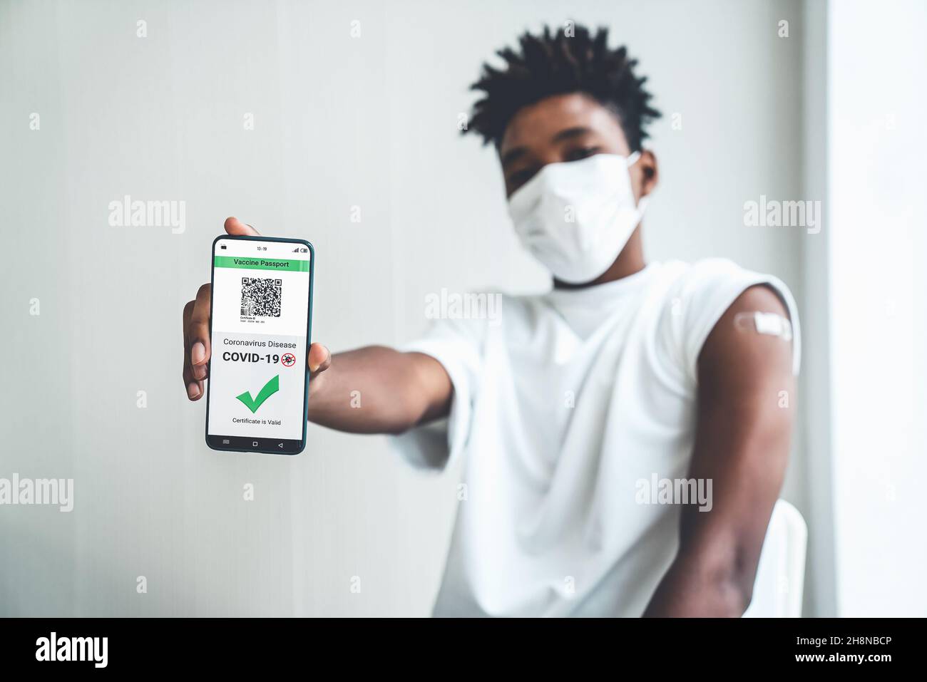 Un adolescent afro-américain présente un passeport vaccinal sur un téléphone portable pour valider l'autorisation de voyage par le document numérique Banque D'Images