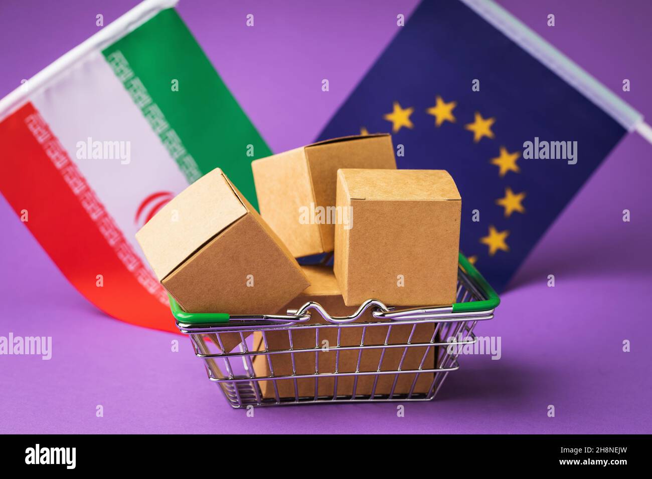 Boîtes en carton dans un panier alimentaire et drapeaux de l'Iran et de l'Union européenne sur fond coloré, le concept de commerce entre pays Banque D'Images