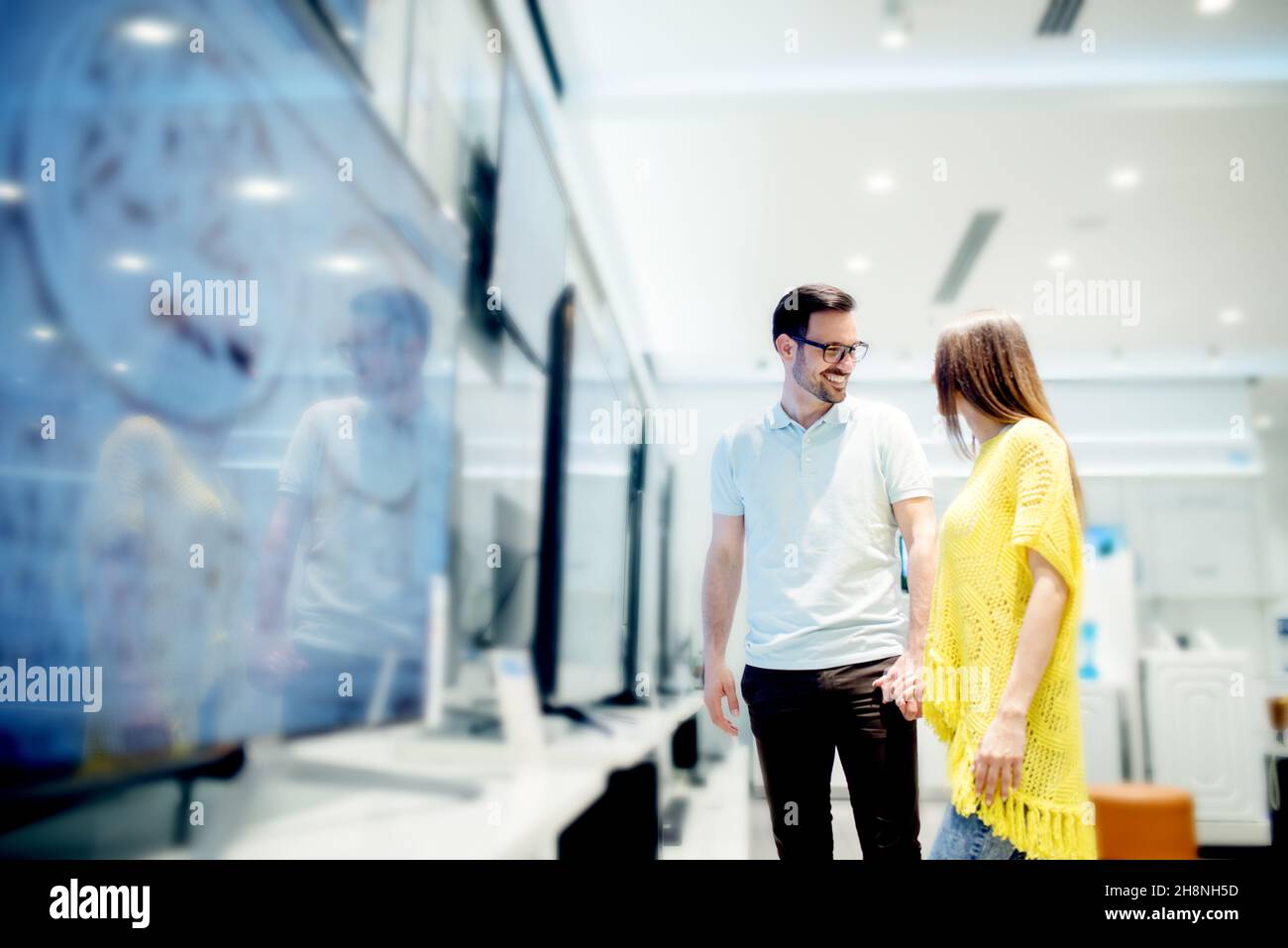 Jeunes couples magasinent dans un magasin de technologie.Acheter un nouveau téléviseur pour leur maison. Banque D'Images