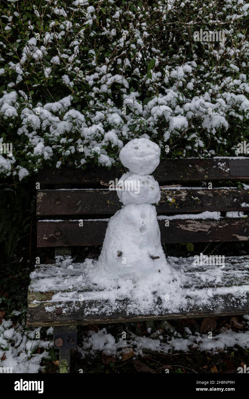 Un petit bonhomme de neige sur un banc de parc, Brungerley Park, Clitheroe, Ribble Valley, Lancashire,ROYAUME-UNI. Banque D'Images