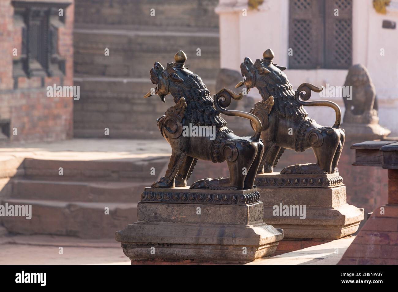 Statues de lion de gardien femelle et mâle en bronze sur la place Durbar, dans la ville médiévale de Newar à Bhaktapur, au Népal. Banque D'Images