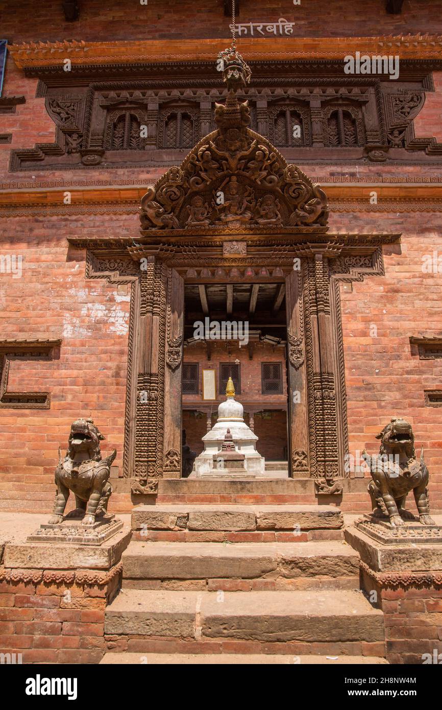 Des lions de gardiens hindous gardent l'entrée du bahal de Tahdhuchhen dans la ville médiévale de Nebari, Bhaktapur, au Népal.Visible à l'intérieur est un mandala en pierre. Banque D'Images