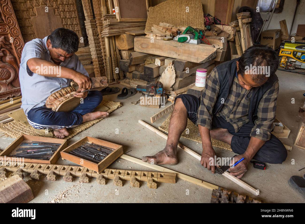Des hommes népalais qui font des sculptures en bois dans un atelier du village médiéval de Bungamati, au Népal. Banque D'Images