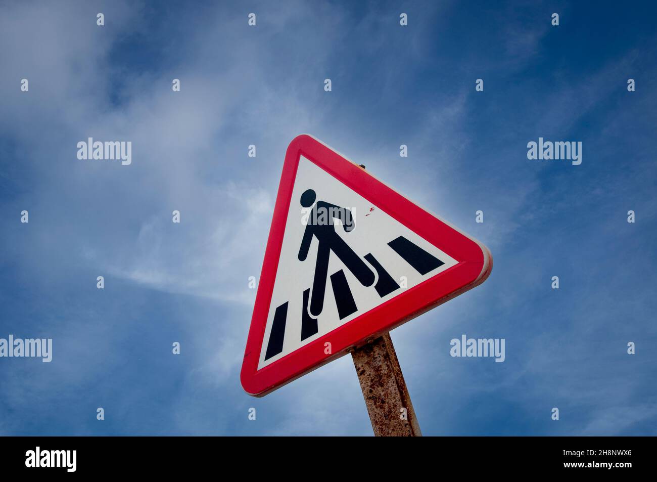 Signe de passage piéton contre un ciel bleu, triangle rouge. Banque D'Images