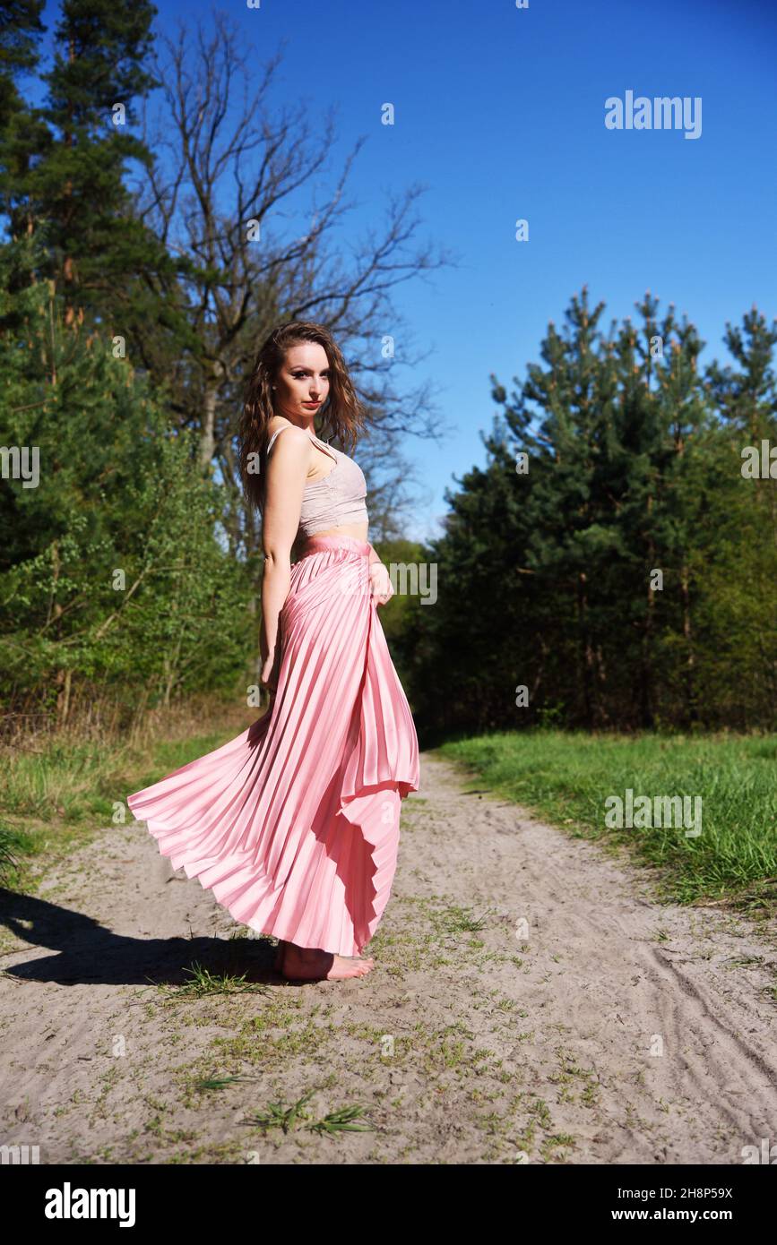 Jolie, jeune femme, tournant avec une jupe pinky dans la forêt.Environnement vert au printemps en Pologne. Banque D'Images