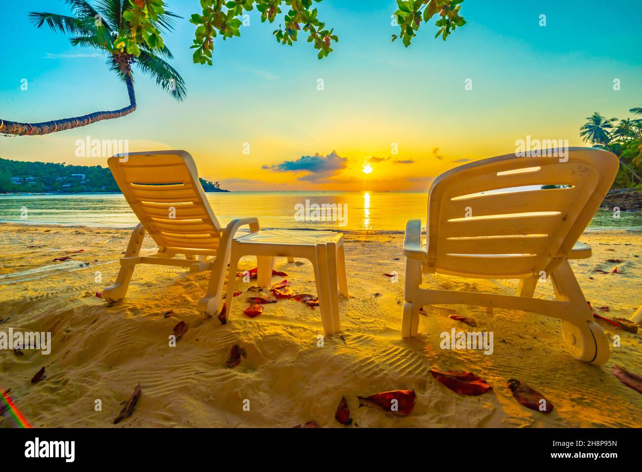 Magnifique coucher de soleil tropical, deux chaises longues, parasol sous le palmier. Sable blanc, vue sur la mer avec horizon, ciel crépuscule coloré, calmnes Banque D'Images
