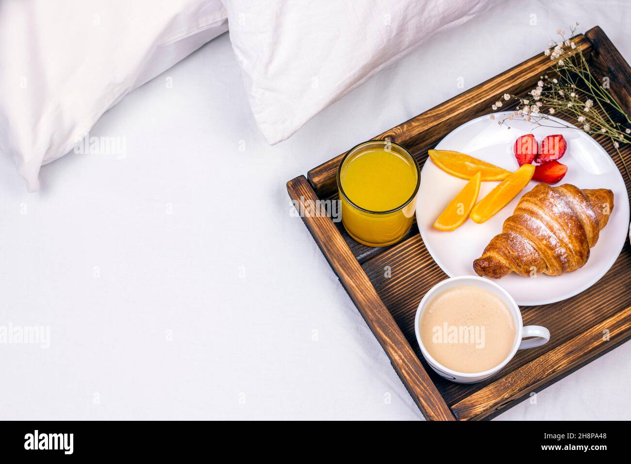 Café, jus d'orange, croissants, lait, fraises et fleurs sur le plateau