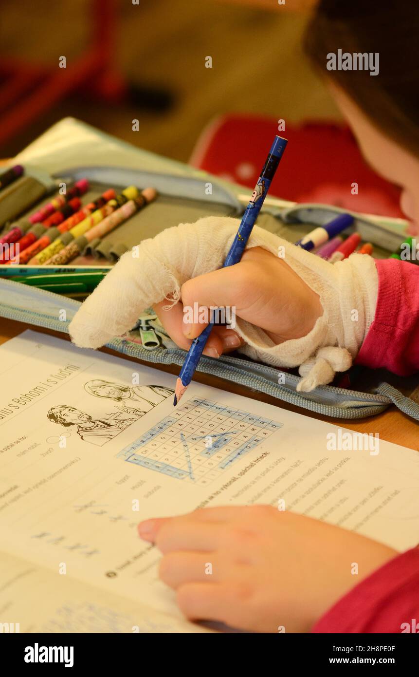 enfants à l'école, élèves en classe, doigt cassé, fille avec doigt cassé à l'école, écriture avec doigt cassé, stylo, fracture, blessure Banque D'Images