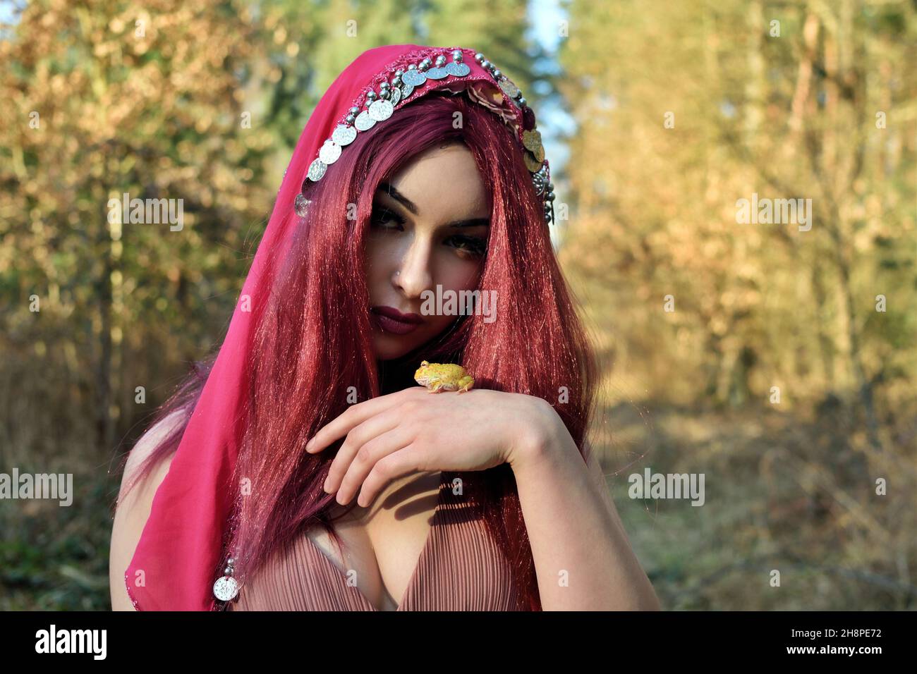 Modèle féminin en forêt, séance photo de jour.Jeune femme aux poils rouges, princesse à la grenouille. Banque D'Images