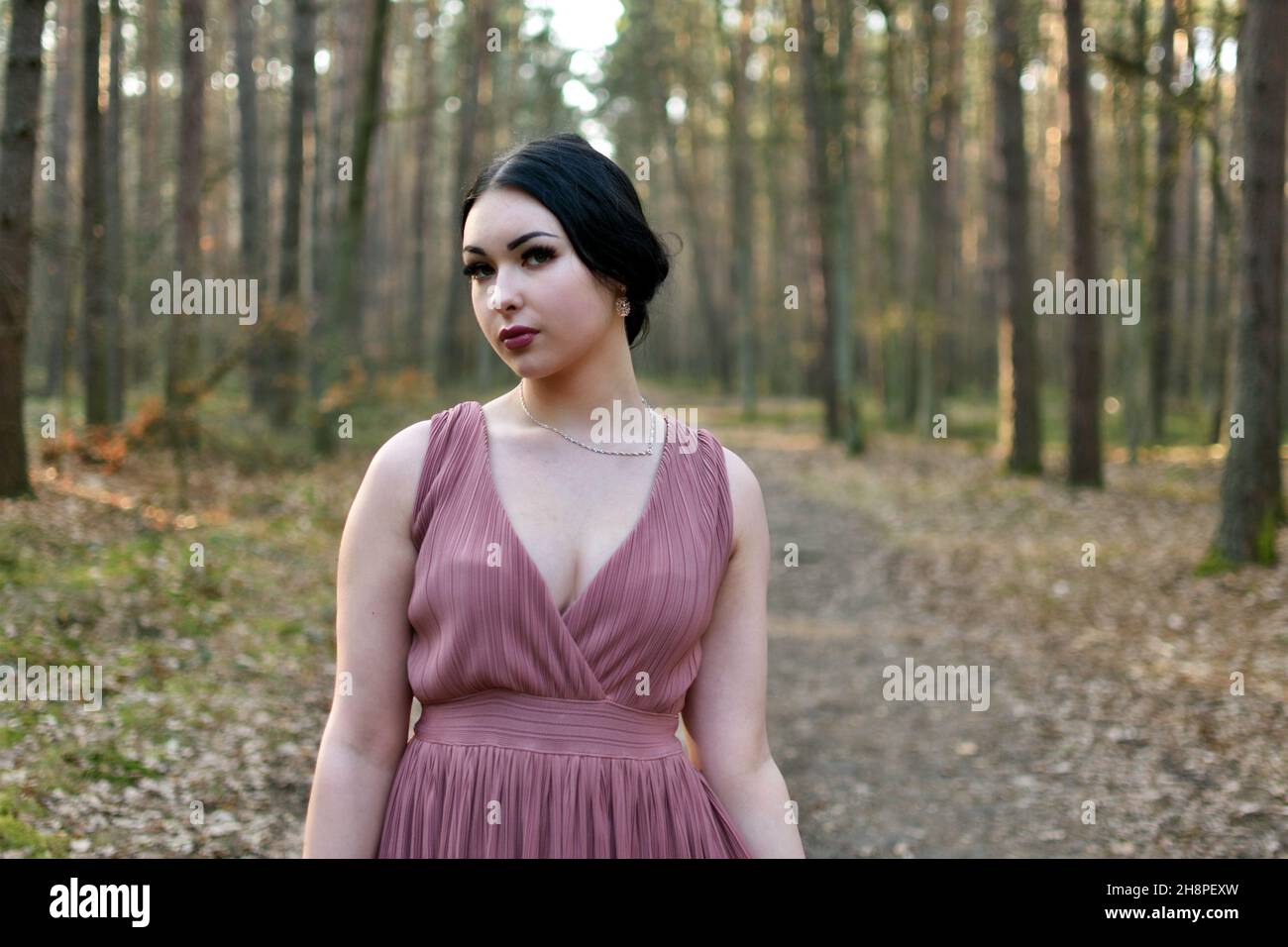 Jeune femme avec robe pourpre dans la forêt.Séance photo de jour, début du printemps en Pologne. Banque D'Images