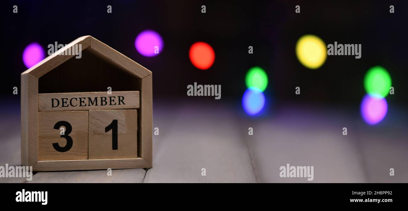 Décorations de Noël sur fond de bois: cubes en bois avec les numéros décembre 31, et guirlande floue multicolore dans le fond.Sélectif Banque D'Images