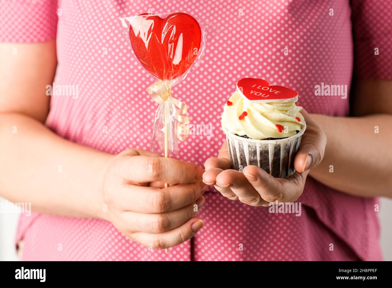 Fille en rose tient coeur en forme Cake avec l'inscription I Love You et rouge lolllipop.Cupcake en forme de coeur Banque D'Images