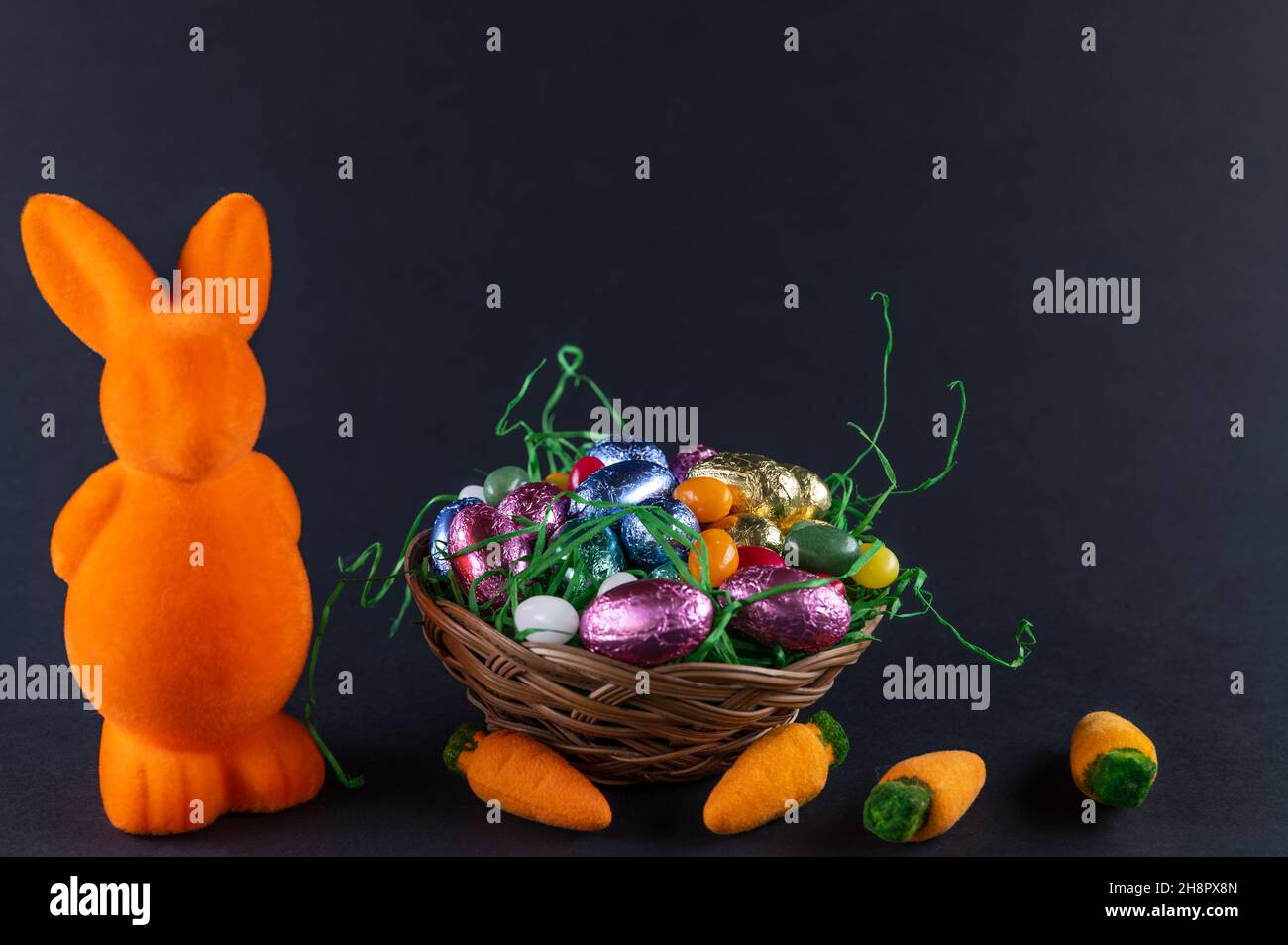 Lapin orange avec carottes et panier de Pâques rempli avec œufs doux Banque D'Images