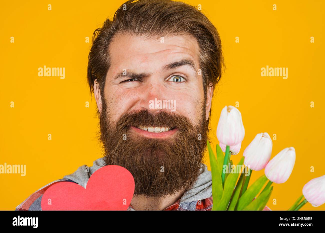 Joyeux homme à barbe avec coeur en papier et fleurs.Amour.Saint-Valentin, joyeux anniversaire, fête des mères. Banque D'Images