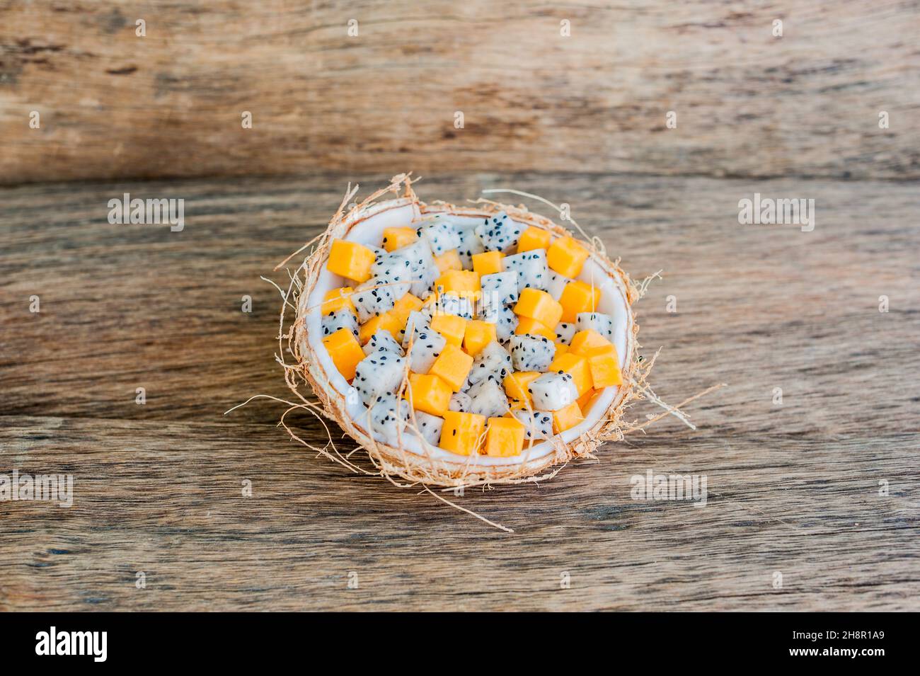 Salade de fruits avec fruits de dragon et papaye en demi noix de coco Banque D'Images