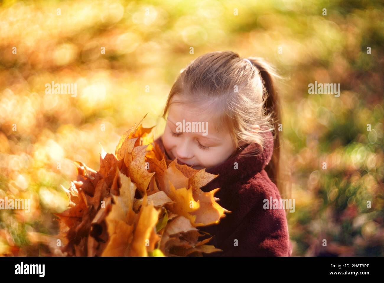 Portrait d'une belle fille dans un manteau de fourrure brun, dans les mains d'une fille feuilles d'érable d'automne, sur le fond de la foliation d'automne. Banque D'Images