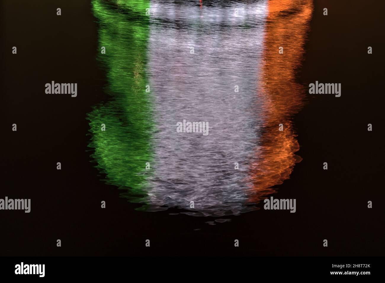 Belle vue rapprochée en soirée de l'éclairage à faisceaux de sonnerie du centre de congrès de Dublin, qui se reflète dans l'eau et imite le drapeau irlandais.Résumé Banque D'Images
