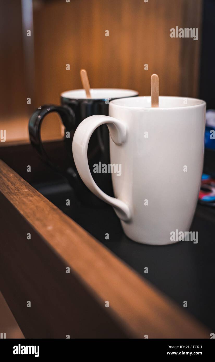 Mise au point sélective d'une tasse à café blanche et noire avec un agitateur en bois Banque D'Images