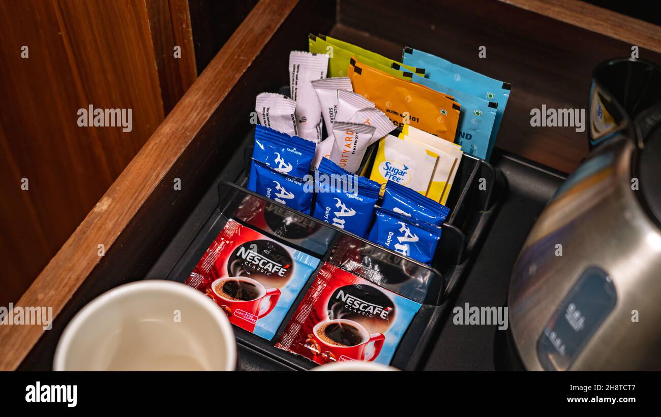 Sélection de sachets de lait en poudre, de sucre et de café au comptoir du minibar. Banque D'Images