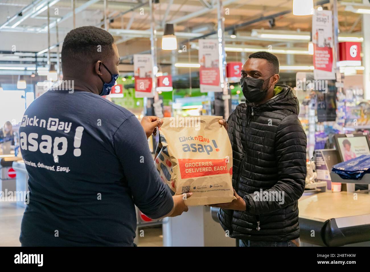 Cape Town, Afrique du Sud - 9 septembre 2021 : le livreur Express Service collecte la commande auprès du personnel au comptoir à l'intérieur de l'épicerie locale Pick n Pay Banque D'Images