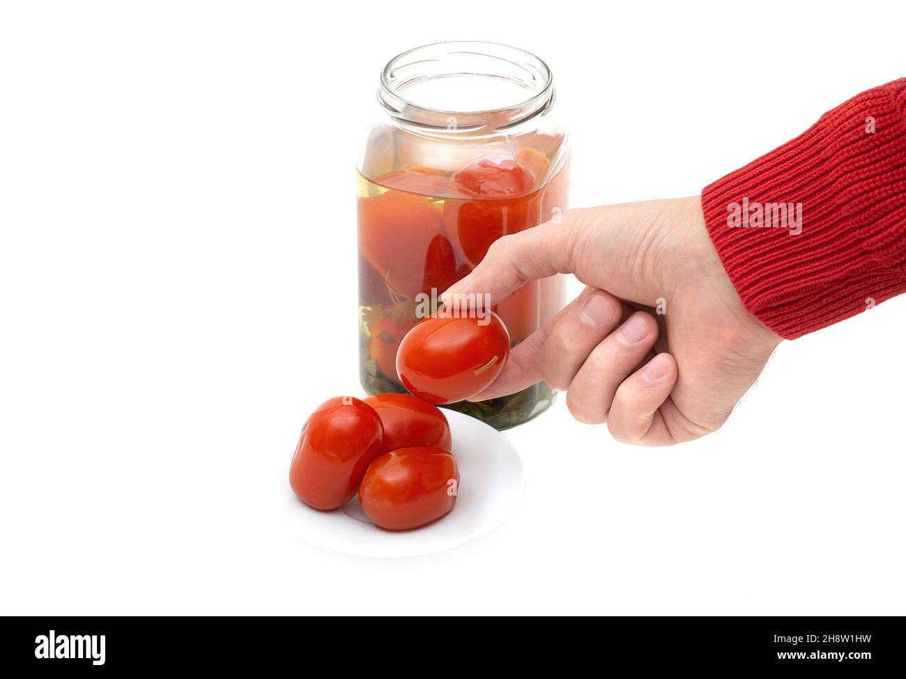 Vue rognée de tomates marinées à la main sur une soucoupe blanche isolée sur du blanc. Banque D'Images