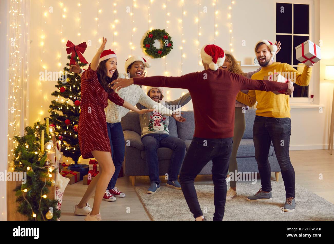 Groupe diversifié de jeunes heureux enthousiastes à l'idée de voir leur ami à la fête de Noël Banque D'Images