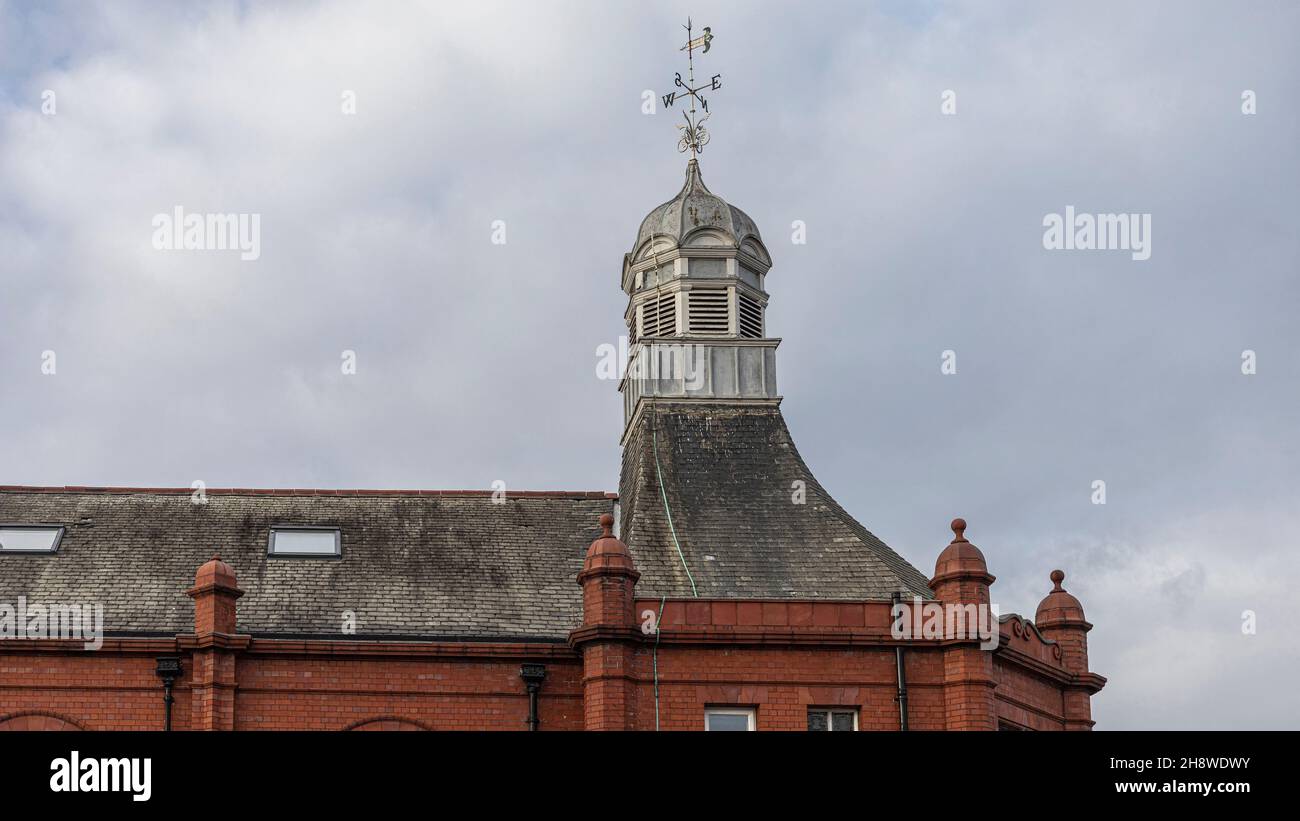 vue sur le toit d'un bâtiment avec une girouette ornée et en briques rouges Banque D'Images