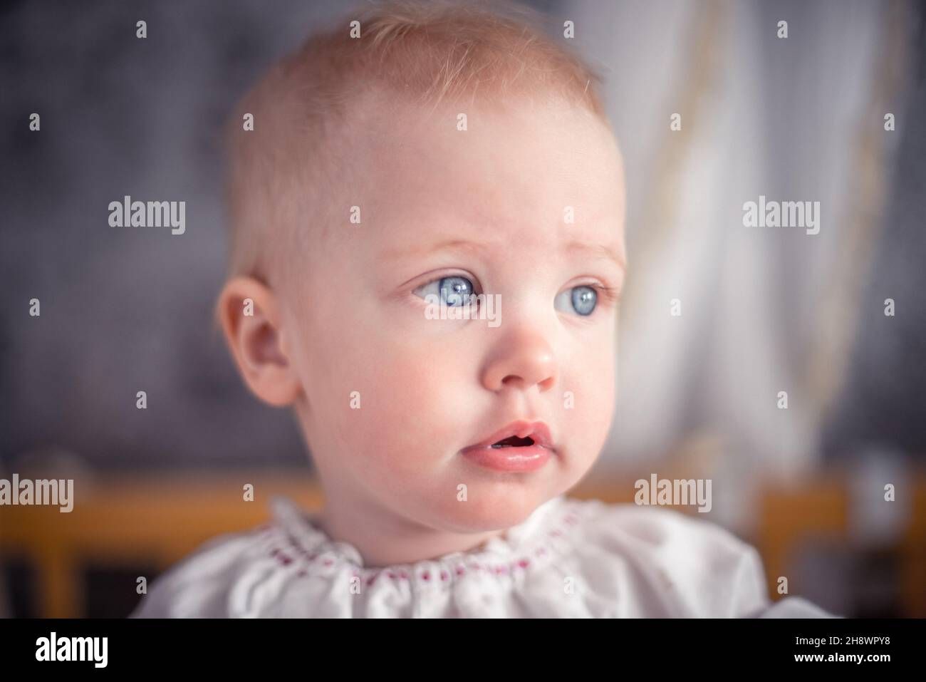 Un mignon petit bébé avec des cheveux blonds et des yeux bleus est à côté Banque D'Images