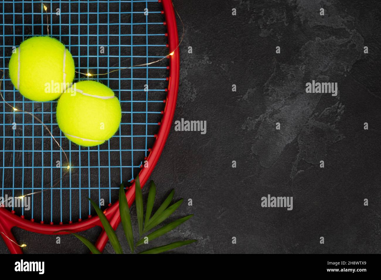 Tennis.Composition sportive avec balles de tennis jaunes sur une raquette avec feuille de palmier sur fond noir avec espace de copie.Le sport et un mode de vie sain.Le Banque D'Images