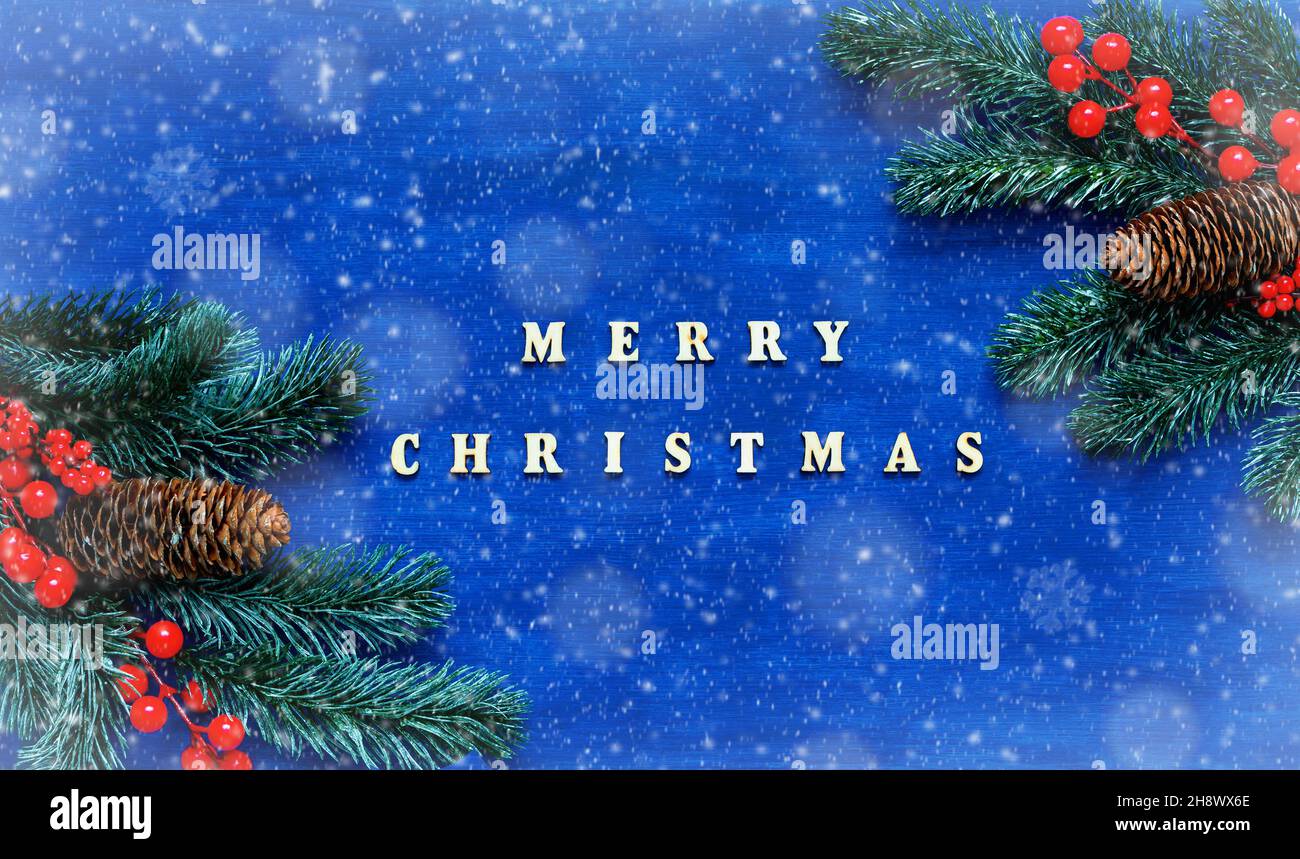 Fond de Noël, inscription Joyeux Noël sur fond de bois bleu, branches de sapin vert, cônes et baies.Joyeux Noël festif c Banque D'Images