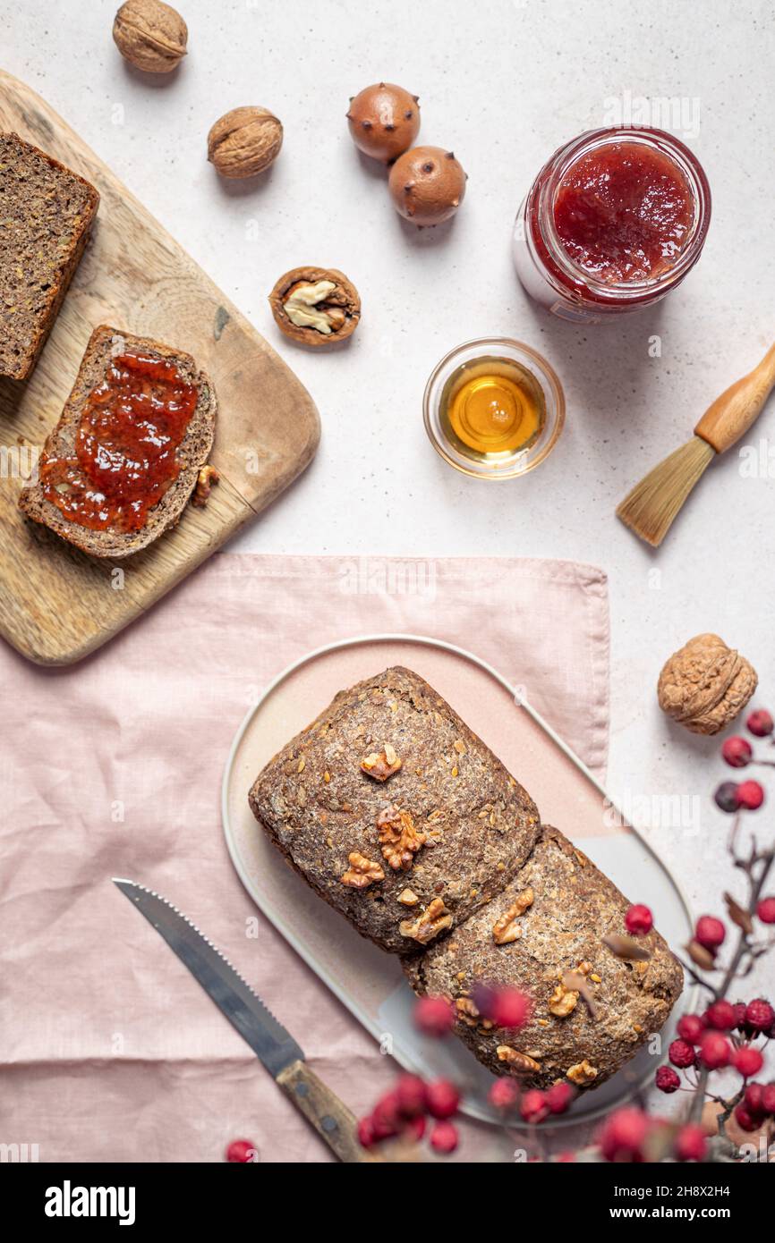 Vue de dessus composition de pain à grains entiers semés avec un pot de miel de confiture et de noyer sur la table près du couteau Banque D'Images