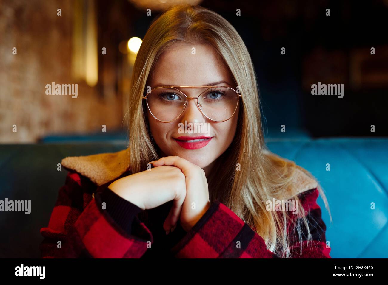 Une jeune femme blonde confiante assise dans un café et regardant l'appareil photo Banque D'Images