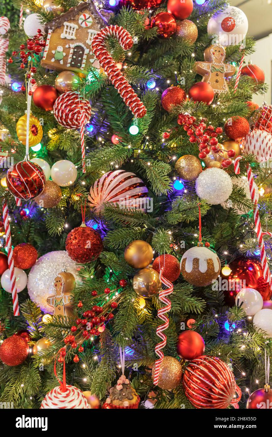 Gros plan d'un pin décoré pour Noël avec des boules, des lumières, du pain d'épice et des bonbons. Banque D'Images