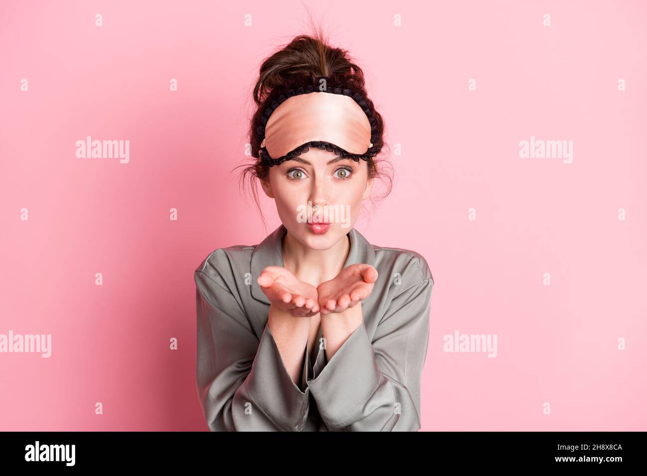 Photo de jeune fille attrayante bouted lèvres envoyer l'air baiser vous portez un masque d'oeil isolé sur fond de couleur rose Banque D'Images