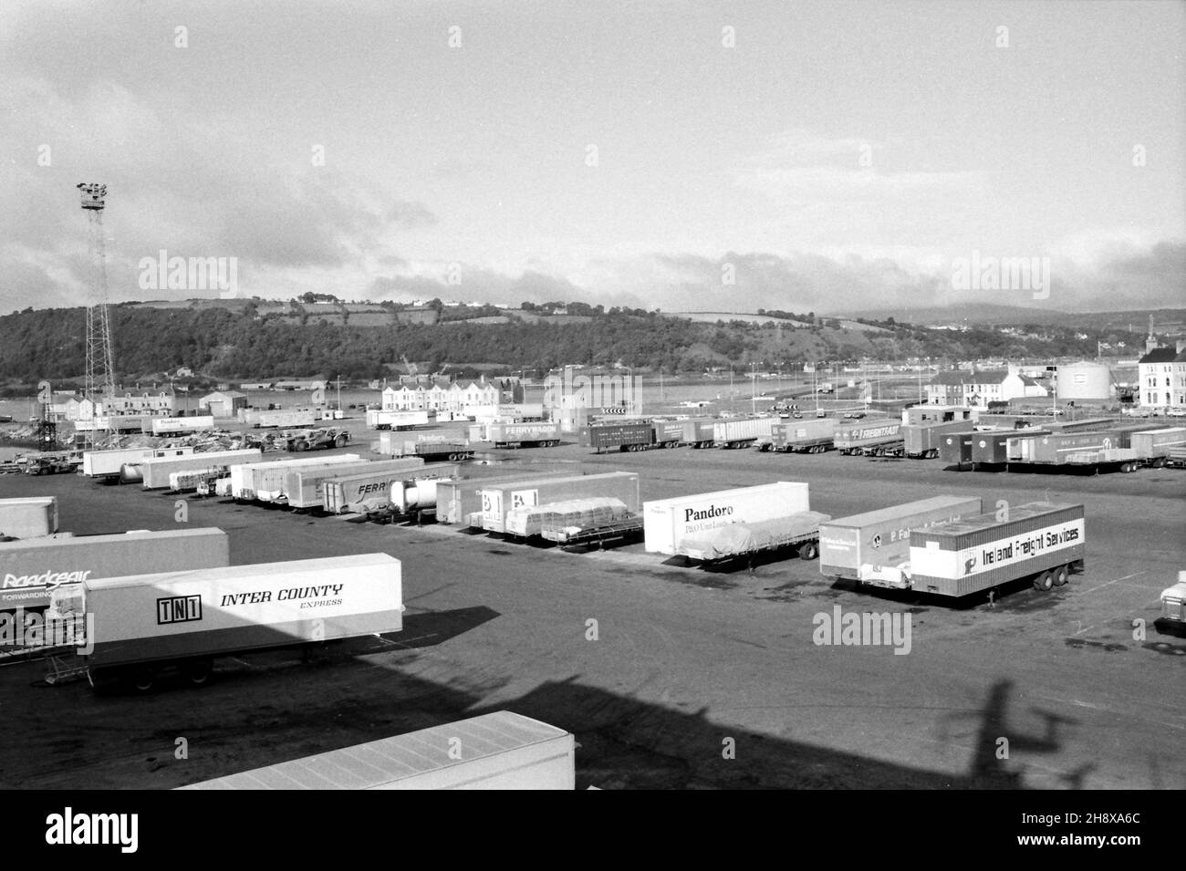 Remorques et conteneurs au terminal de ferry de Larne, en Irlande du Nord.Avec des maisons sur Coastguard Road à gauche du centre et des bâtiments au bout de Olderfleet Road à droite.Prise de P&O Freight Ferry M/V Bison.Février 1984 Banque D'Images