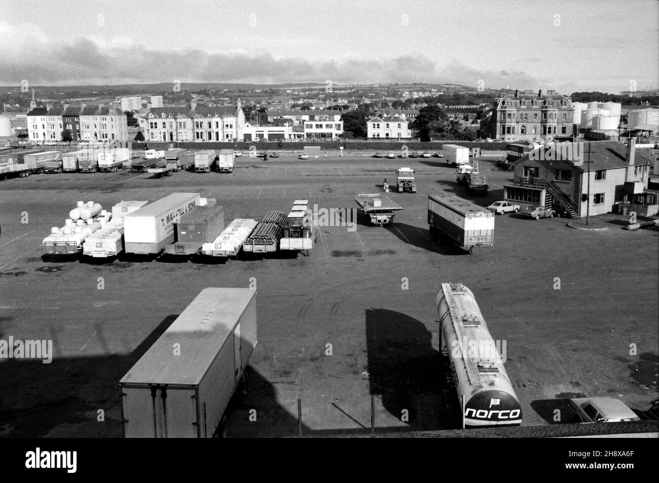 Remorques et conteneurs au terminal de ferry de Larne, en Irlande du Nord.Avec des maisons et le bâtiment H.M. Coastguard sur la route Olderfleet au-delà.Prise de P&O Freight Ferry M/V Bison.Février 1984 Banque D'Images