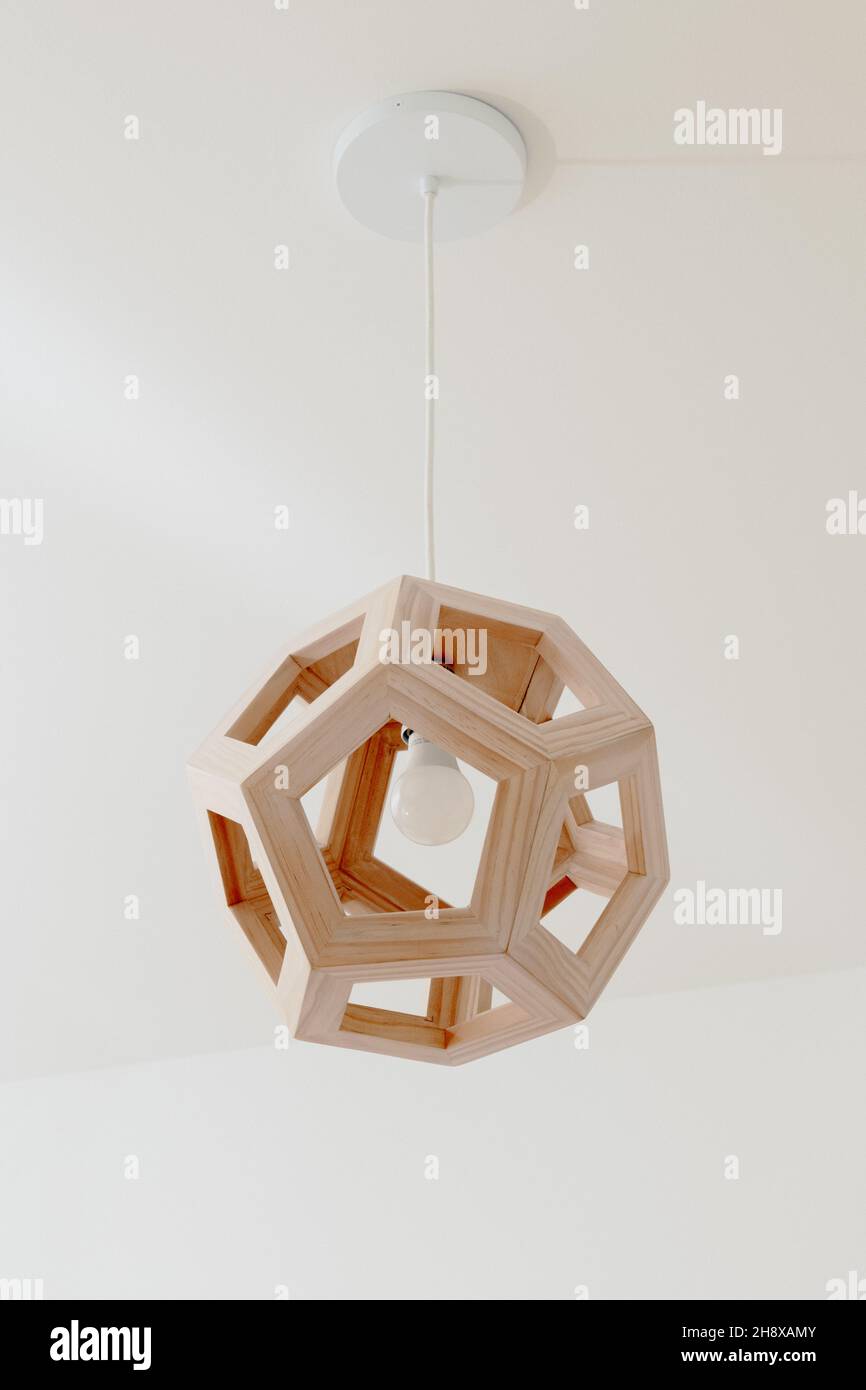 Luminaire moderne en bois géométrique contre plafond blanc Banque D'Images