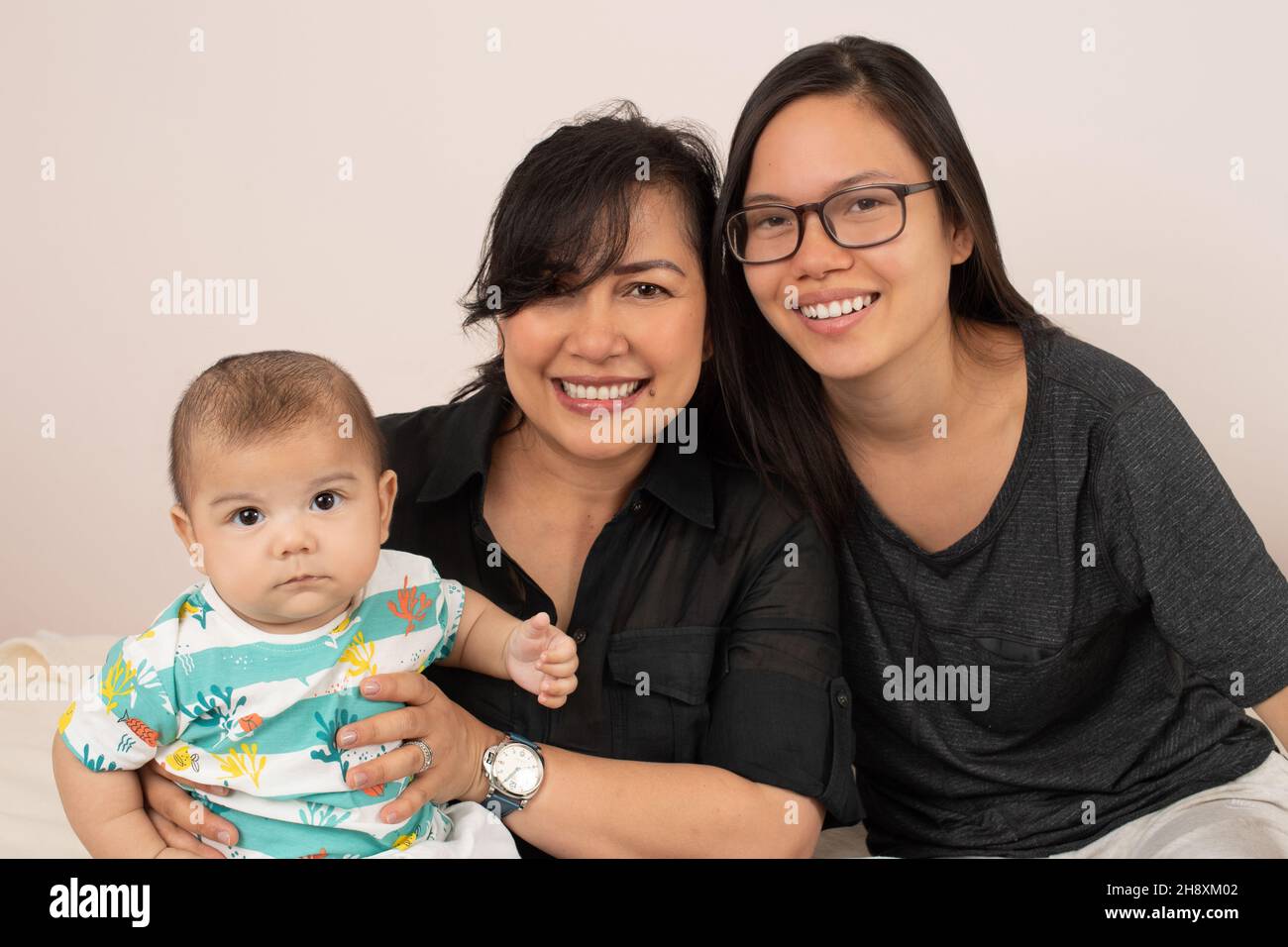 bébé garçon de 3 mois avec une sœur âgée de 20 ans et une mère, portrait, regardant l'appareil photo Banque D'Images