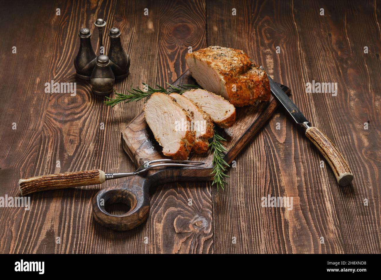 Joint de collier de porc cuit au four sur une planche à découper en bois Banque D'Images