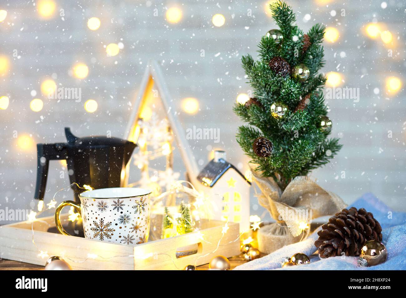 Décoration de Noël sur la table avec une tasse et une cafetière.Arbre de Noël, plateau - petit-déjeuner du matin du nouvel an avec lumières de fées et verres. Banque D'Images